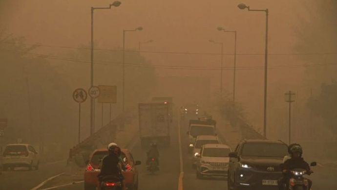 Pengendara motor melintas di Jembatan Kahayan yang diselimuti asap di Palangka Raya, Kalimantan Tengah, Minggu, 11 Oktober 2026.