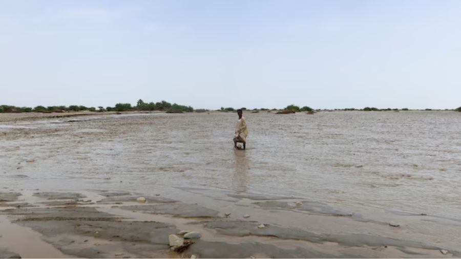 Seseorang berjalan melewati air banjir, di Port Sudan <b>(Reuters)</b>