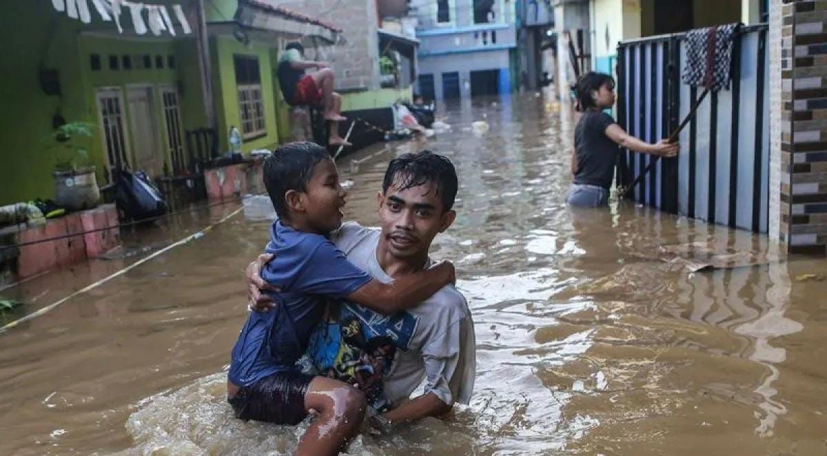 Warga menggendong anaknya melintasi banjir di kawasan Jalan Jembatan 1, Kramat Jati, Jakarta, Senin (3/3/2025). Kawasan di sepanjang aliran Kali Ciliwung tersebut terendem banjir setinggi 30 cm - 130 cm akibat luapan Bendungan Katulampa yang sudah me <b>(Antara)</b>