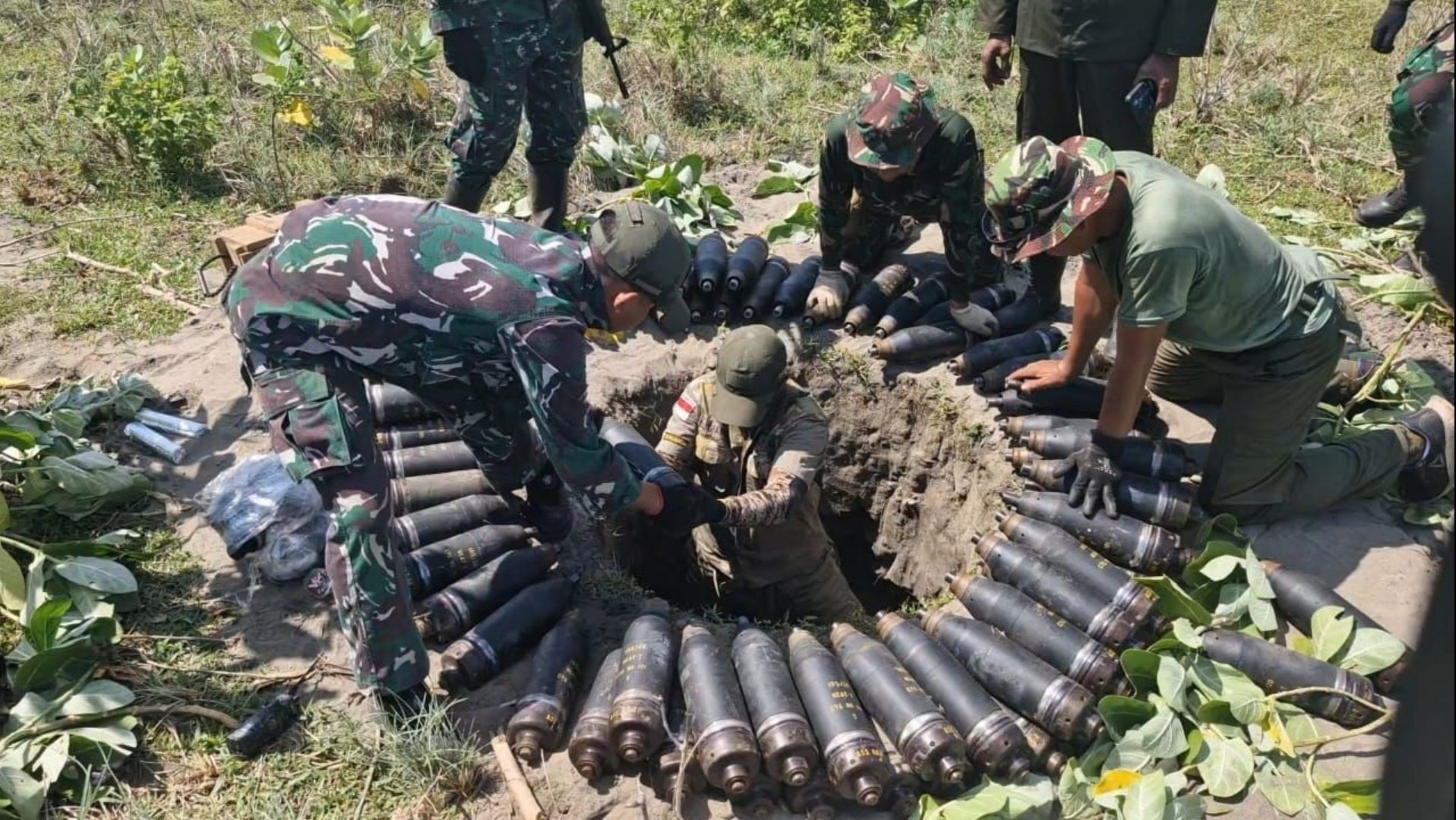 Anggota TNI memasukkan amunisi kedaluwarsa ke lubang untuk dimusnahkan. 