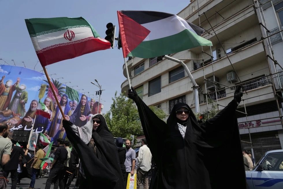 Pendemo Iran mengibarkan bendera Iran dan Palestina dalam aksi anti-Israel di Tehran. <b>(AP News)</b>