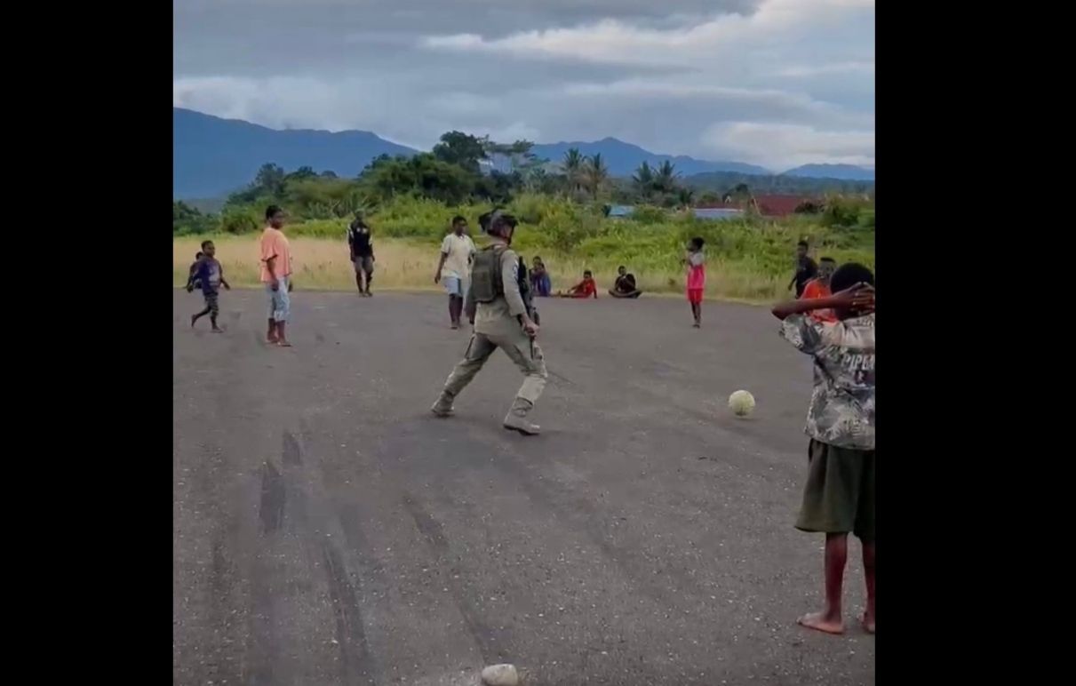 Personel Satgas Ops Damai Cartenz bermain sepak bola bersama anak-anak warga. 