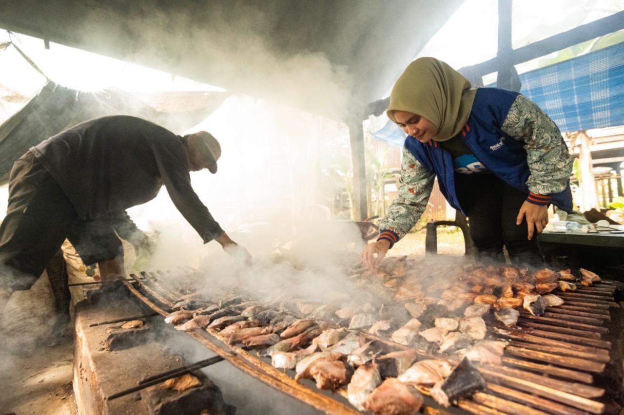 Pelaku UMKM binaan BRI tengah mengolah hasil tangkapan laut melalui metode pengasapan. BRI konsisten mendukung pemberdayaan UMKM agar mampu naik kelas dan berdaya saing. <b>(BRI)</b>
