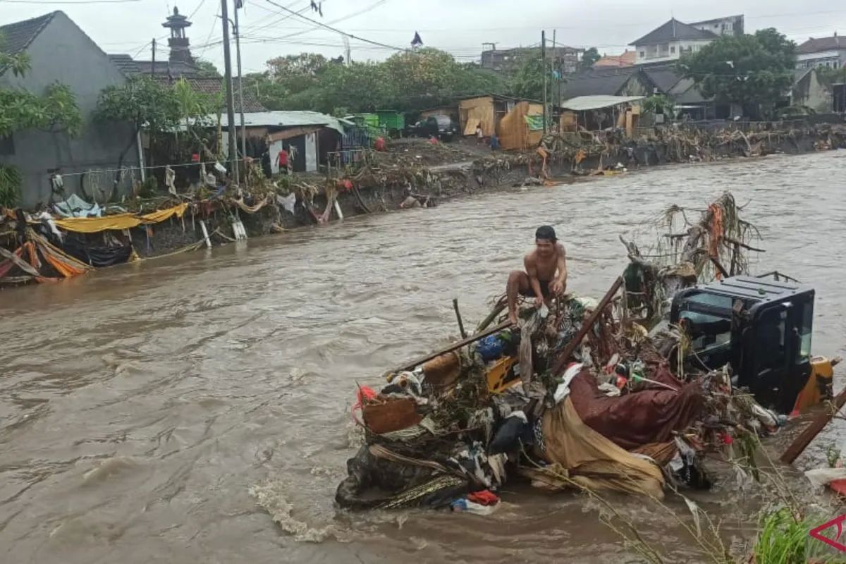 Seorang warga duduk di atas sebuah ekskavator yang hanyut terbawa banjir di Tukad Badung, Denpasar Barat, Bali, Rabu, 10 September 2025. <b>(ANTARA)</b>