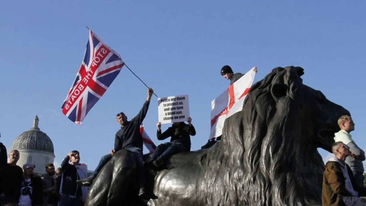 Para demonstran anti-imigran mengibarkan bendera dan spanduk, sementara seorang demonstran pro-polisi secara bersamaan juga membawa spanduk di London, Inggris, pada 13 September 2025. <b>(ANTARA)</b>