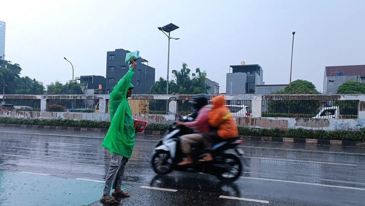 Pedagang jas hujan saat menawarkan dagangannya di tepi jalan ketika turun hujan di Jakarta, Rabu, 15 Oktober 2025. ANTARA/Khaerul Izan <b>(Antara)</b>