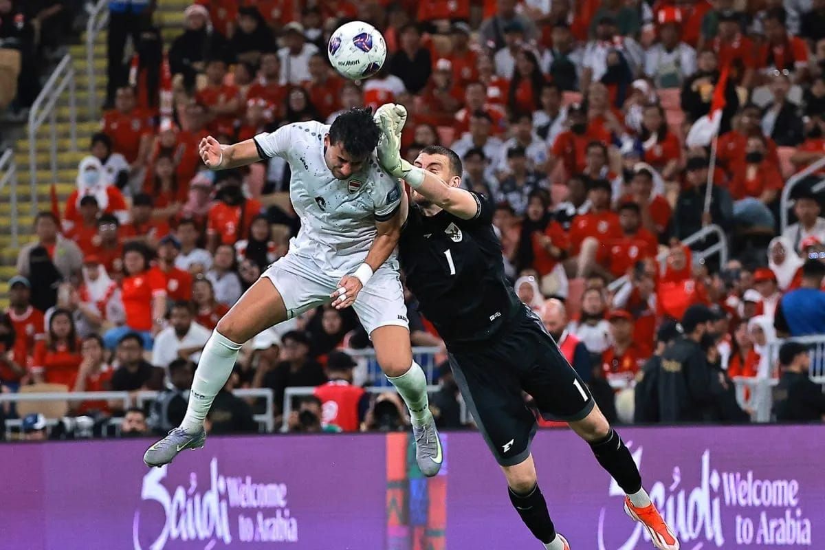 Penjaga gawang Timnas Indonesia Maarten Paes (kanan) mendahului meninju bola sebelum disundul pesepak bola Irak Munaf Younus (kiri) dalam putaran keempat Kualifikasi Piala Dunia 2026 zona Asia di Stadion King Abdullah Sport City, Jeddah, Arab Saudi,  <b>(Antara)</b>