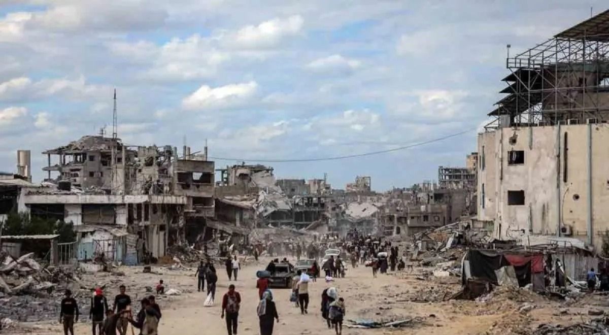 Penduduk Palestina berjalan melintasi bangunan-bangunan yang hancur saat kembali ke Khan Younis, di Jalur Gaza selatan, Minggu, 12 Oktober 2025. Kesepakatan gencatan senjata antara Israel dan Hamas berlaku sejak Jumat, 10 Oktober lalu. (ANTARA FOTO/X <b>(Antara)</b>