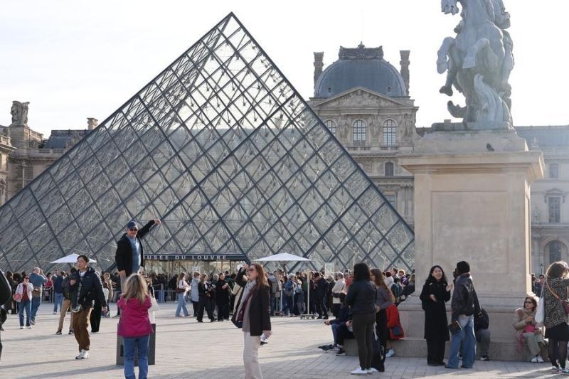 Para turis berfoto di depan bangunan Piramida Louvre di Paris, Prancis pada Rabu 22 Oktober 2025 waktu setempat. Museum ini kembali dibuka pada Rabu pagi, tiga hari setelah pencurian perhiasan bernilai puluhan juta euro. (Xinhua/Zhang Baihui) <b>(Antara)</b>