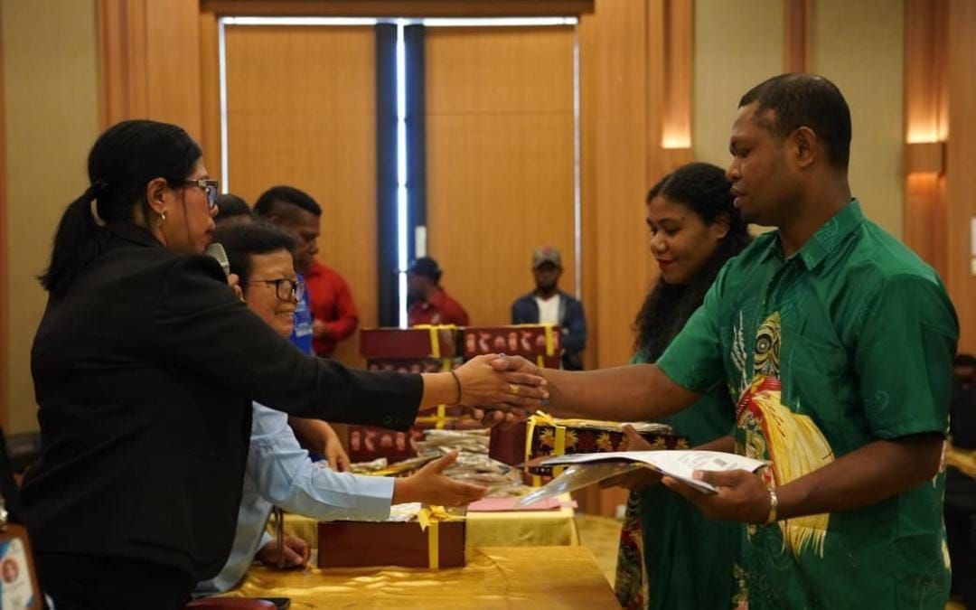 Penyerahan Dokumen Catatan Sipil oleh  Sekretaris Disdukcapil Mimika Damaris  Tappi kepada pasangan peserta program.  <b>(Freeport Indonesia)</b>