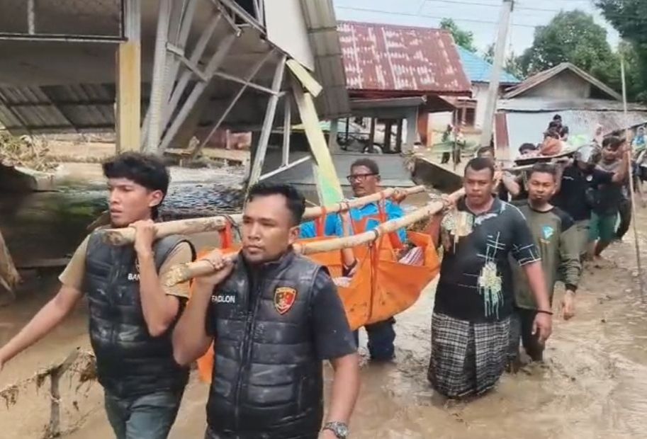 Polisi dan warga menggotong jenazah santri yang hanyut di Aceh. 