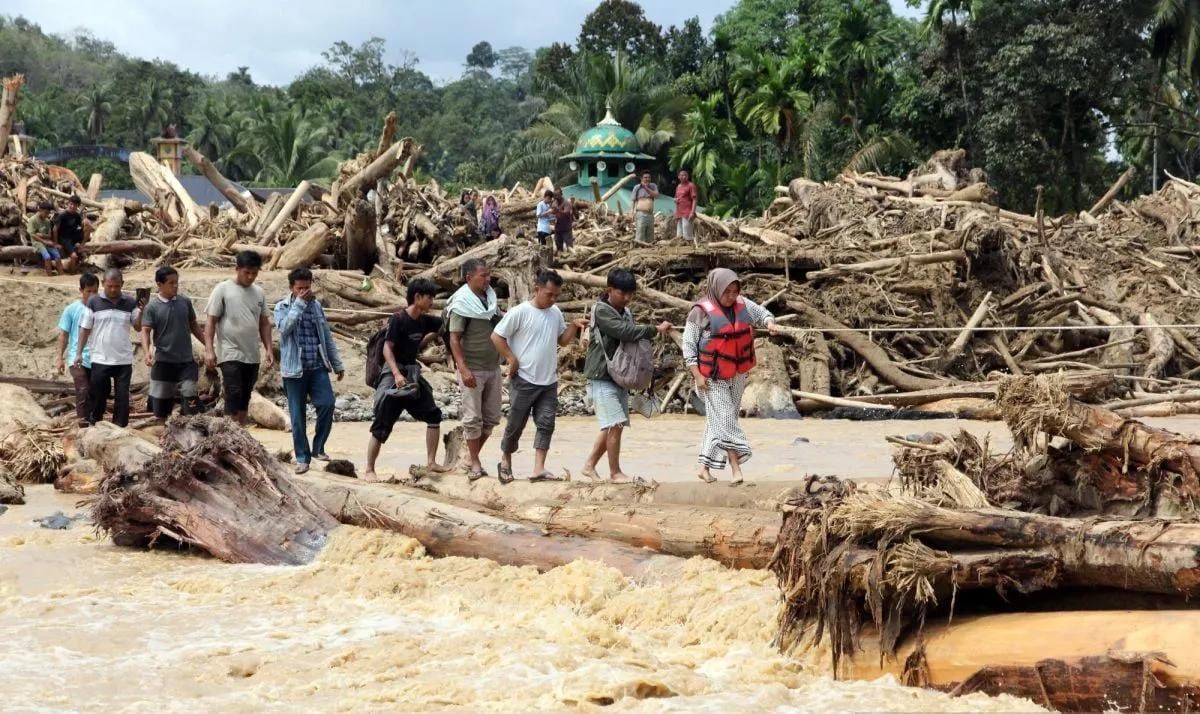 Arsip - Warga berjalan melintasi sungai dengan jembatan darurat di Desa Aek Garoga, Kecamatan Batang Toru, Kabupaten Tapanuli Selatan, Sumatera Utara, Sabtu (29/11/2025). Warga terpaksa melintasi jembatan darurat dari batang kayu akibat jalan dan jem <b>(Antara)</b>