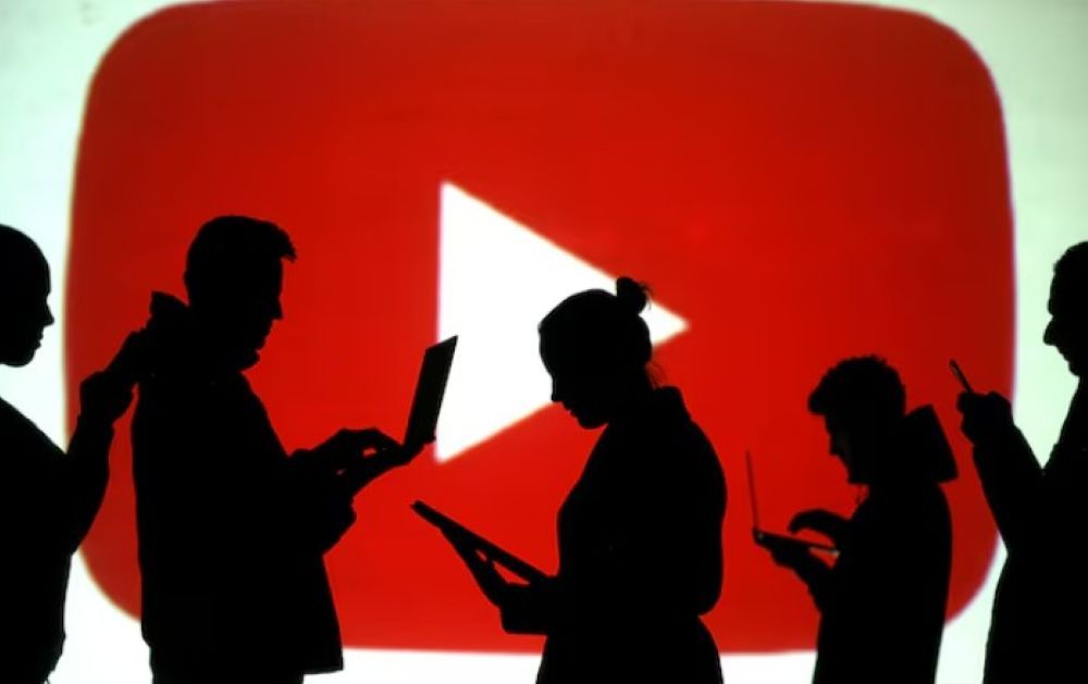 Siluet pengguna laptop dan perangkat seluler terlihat di samping proyeksi layar logo Youtube dalam ilustrasi gambar ini yang diambil pada 28 Maret 2018. (Foto: Dok/Dado Ruvic/Reuters) 