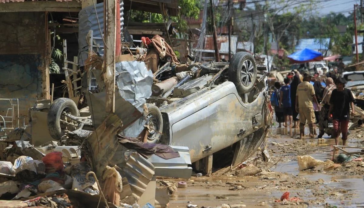 Sejumlah warga melintas di dekat mobil warga yang terbawa arus banjir di kawasan Desa Bukit Tempurung, Kota Kuala Simpang, Kabupaten Aceh Tamiang, Aceh, Rabu, 3 Desember 2025. ANTARA FOTO/Syifa Yulinnas/bar <b>(Antara)</b>
