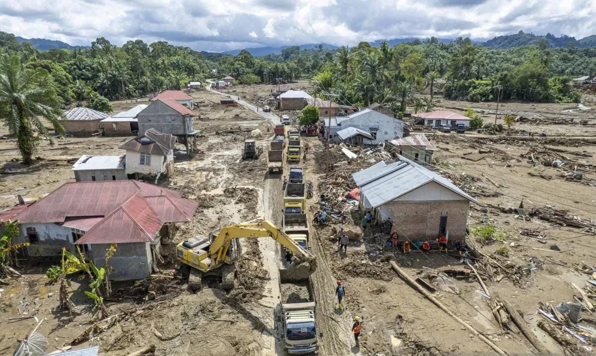 Foto udara alat berat membersihkan reruntuhan rumah, kayu, dan lumpur sisa bencana banjir bandang ke atas truk yang mengantre di Jorong Kayu Pasak, Nagari Salareh Aia, Palembayan, Agam, Sumatera Barat, Selasa 9 Desember 2025. Pemerintah mengerahkan b <b>(Antara)</b>