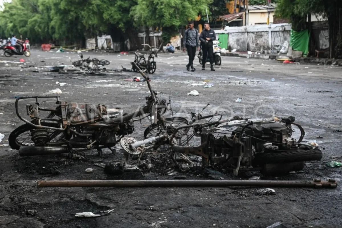 Warga melintas di samping sepeda motor yang terbakar pascakericuhan di kawasan Kalibata, Jakarta, Jumat, 12 Desember 2025. ANTARA FOTO/Sulthony Hasanuddin/nym. <b>(Antara)</b>