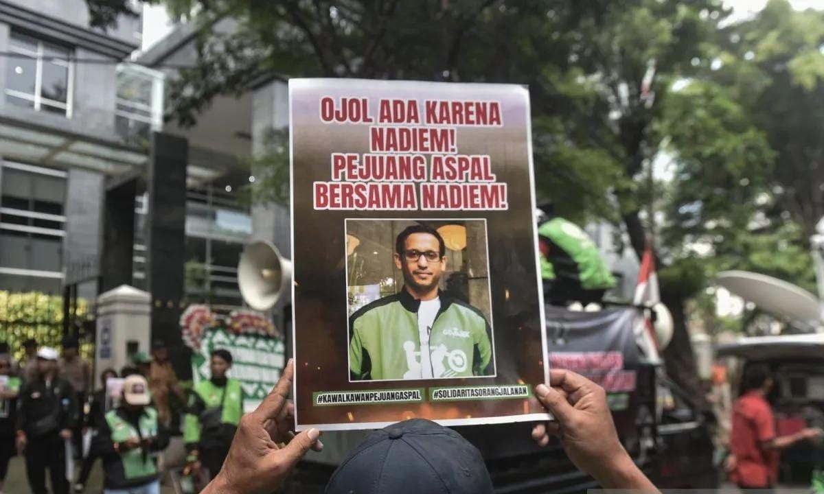 Pengemudi ojek daring memegang poster dukungan kepada tersangka kasus dugaan korupsi dalam digitalisasi pendidikan dan pengadaan laptop Chromebook di Kemendikbudristek tahun di 2019-2022 Nadiem Makarim di depan PN Jakarta Pusat, Senin 5 Januari 2026. <b>(Antara)</b>