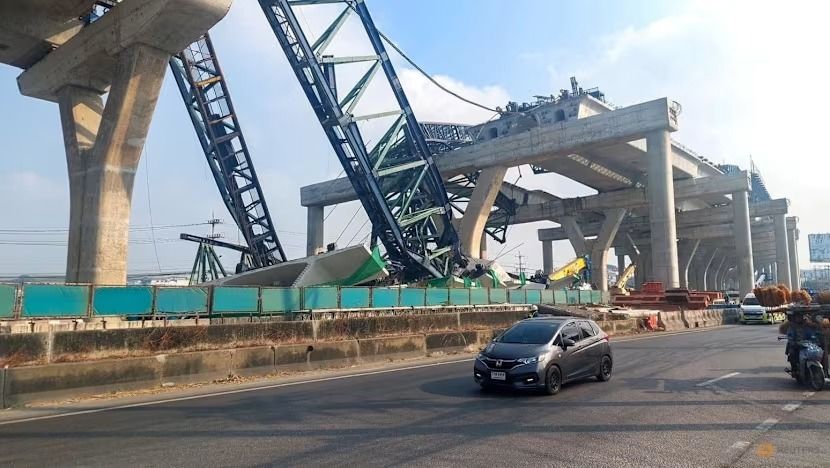 Mobil-mobil melintas di samping sebuah crane yang roboh dan menghancurkan dua kendaraan selama pembangunan jalan layang di Provinsi Samut Sakhon, Thailand, pada 15 Januari 2026. (Foto: Reuters/Asosiasi Pekerja Penyelamat Thailand) <b>(CNA)</b>