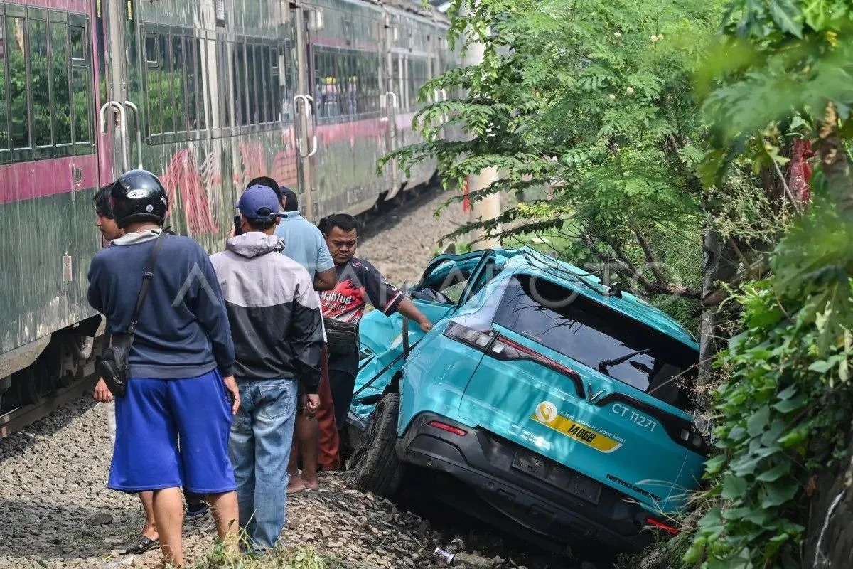 Kereta api (KA) jarak jauh melintas di samping taksi listrik Green SM yang rusak pascakecelakaan KRL Commuter Line dan KA Argo Bromo Anggrek di Stasiun Bekasi Timur, Bekasi, Jawa Barat, Selasa (28/4/2026). Komite Nasional Keselamatan Transportasi (KN <b>(Antara)</b>