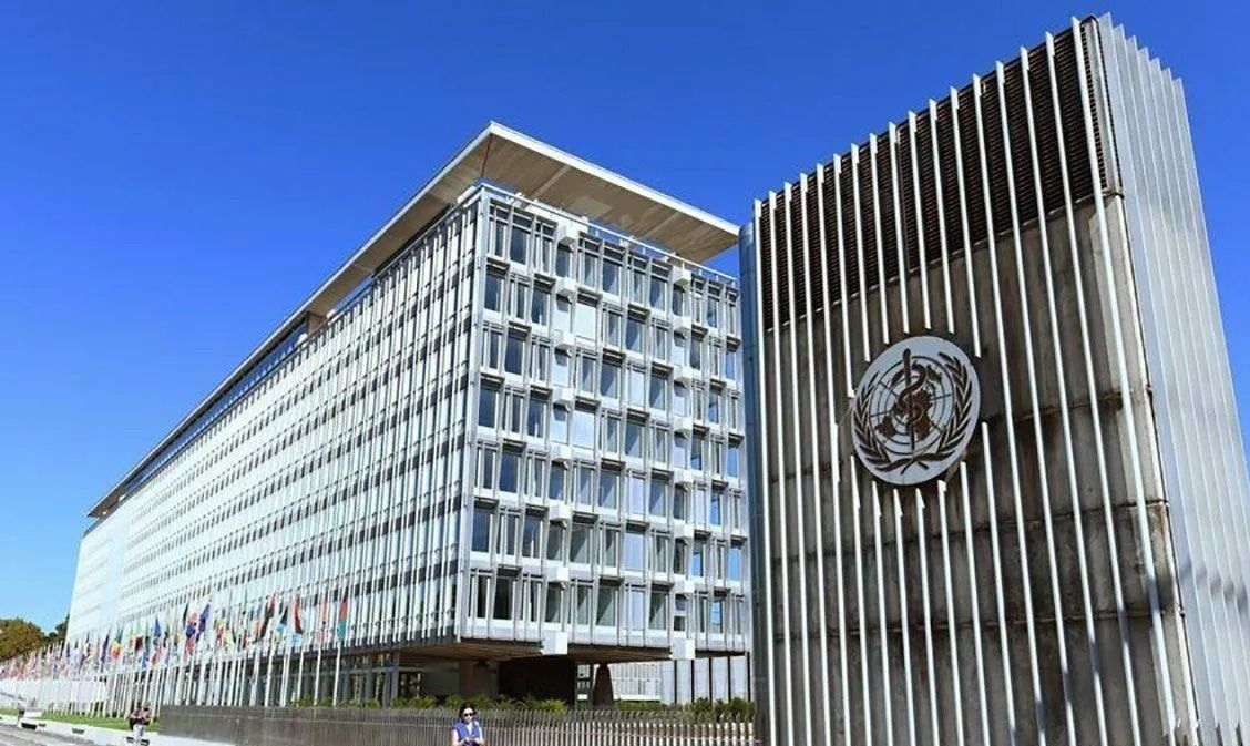 Logo Organisasi Kesehatan Dunia (WHO) dengan kantor pusat WHO di latar belakang di Jenewa, Swiss, Minggu (21/5/2023). ANTARA/Xinhua/Lian Yi/aa. <b>(Antara)</b>