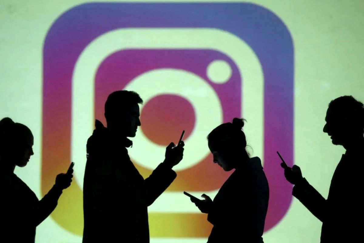 Siluet pengguna ponsel pintar dengan latar proyeksi layar logo Instagram. (REUTERS/Dado Ruvic)
