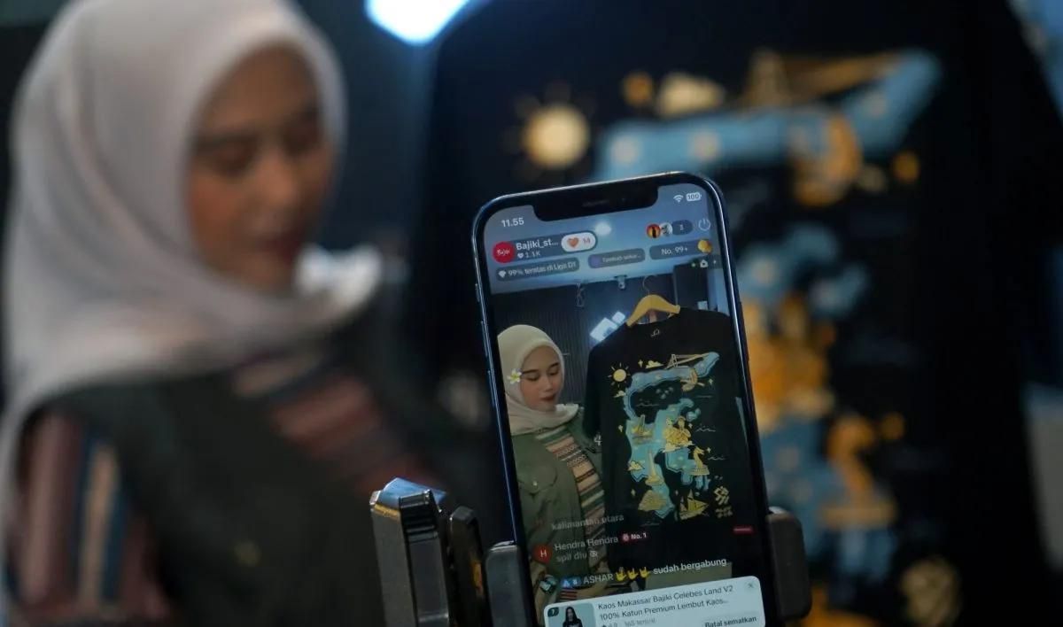 Pramuniaga menjual pakaian melalui aplikasi belanja daring (e-commerce) di gerai Bajiki Store, Makassar, Sulawesi Selatan, Rabu, 20 Juni 2026. Pemerintah akan mewajibkan marketplace atau e-commerce memberikan diskon 50 persen biaya layanan kepada pel <b>(Antara)</b>