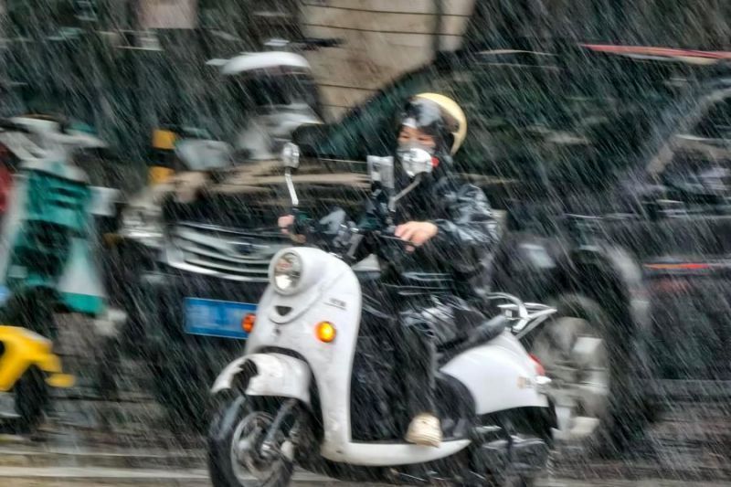Seorang warga mengendarai skuter di tengah hujan di Distrik Xixiangtang, Nanning, Daerah Otonom Etnis Zhuang Guangxi, China, pada Minggu, 5 Juli 2026. (Xinhua/Yu Xiangquan) <b>(Antara)</b>