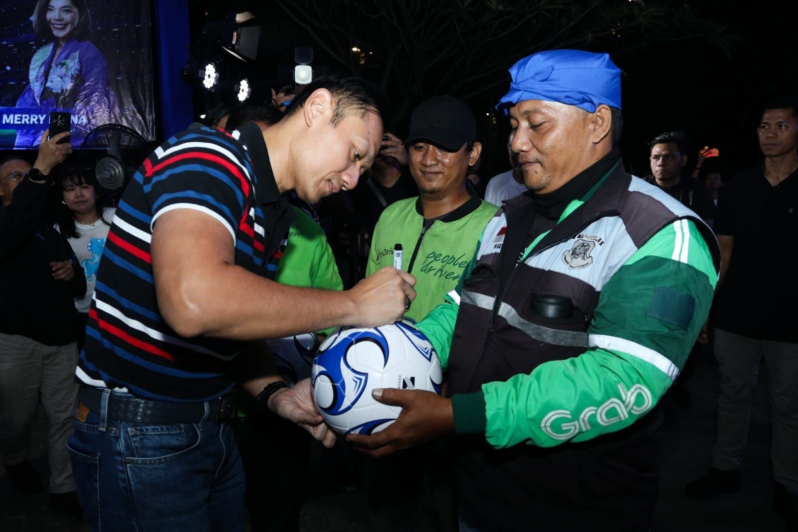 AHY menandatangani bola yang diberikan kepada ojol. 
