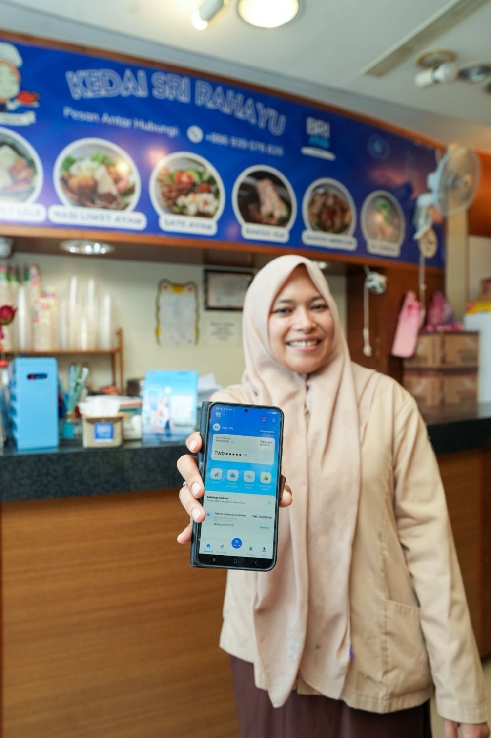 Seorang WNI pengusaha kuliner di Taiwan menunjukkan aplikasi BRImo Taiwan. Layanan digital banking ini mempermudah transaksi harian, pembayaran QR, hingga remitansi bagi diaspora dan Pekerja Migran Indonesia (PMI).