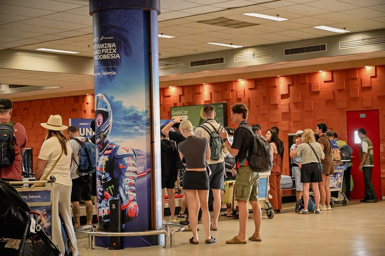 Para pengunjung dan wisatawan yang baru tiba di Bandara Internasional Lombok melintasi pilar terminal yang menampilkan visual aksi pembalap MotoGP.
