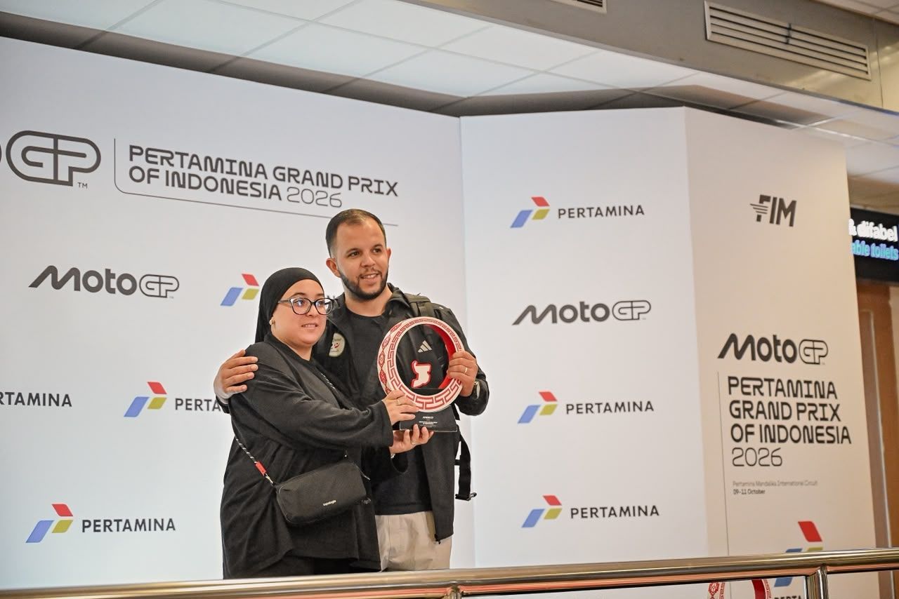 Pengunjung berpose di area foto khusus yang dilengkapi replika podium dan trofi Pertamina Grand Prix of Indonesia 2026.