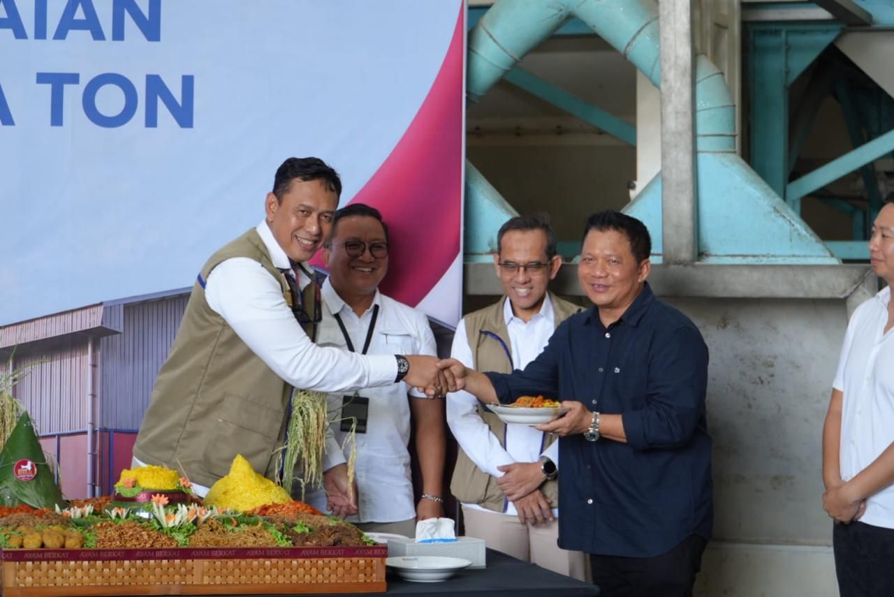 Direktur Utama Perum BULOG Ahmad Rizal Ramdhani berjabat tangan dan menyerahkan potongan tumpeng kepada perwakilan undangan sebagai simbol kolaborasi lintas sektor dalam pencapaian target pengadaan pangan nasional.