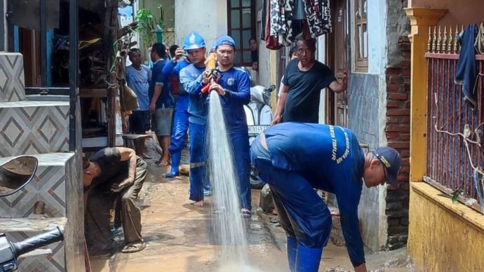 Petugas Suku Dinas (Sudin) Sumber Daya Air (SDA) Jatinegara menyemprotkan air untuk membersihkan lumpur sisa banjir di wilayah Tanah Rendah, Kampung Melayu, Jakarta Timur, Rabu (5/3/2025).