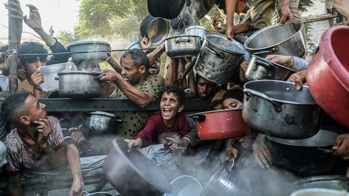 Arsip foto - Seorang anak bersama pengungsi lainnya menunggu pembagian makanan gratis dari pusat distribusi makanan di Kota Gaza, Palestina (14/7/2025). 