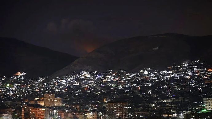 Asap membubung dari Gunung Qasioun setelah serangan udara Israel di Damaskus, Suriah.