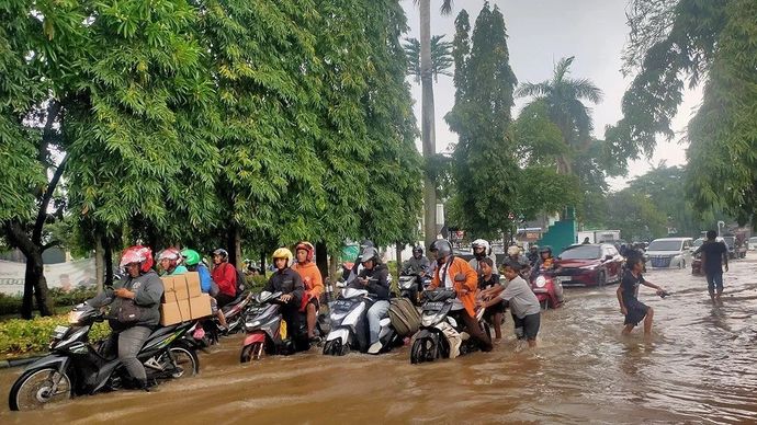 Sejumlah pengendara sepeda motor tengah melintas di jalan yang terendam banjir akibat luapan Kali Pesanggrahan di Jalan Pesanggrahan, Kembangan Selatan, Kembangan, Jakarta Barat, Selasa (4/3/2025)