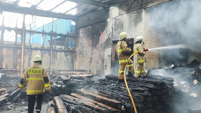 Petugas Gulkarmat masih melakukan proses pendinginan di lokasi gudang wallpaper di Pelabuhan Muara Baru Penjaringan Jakarta Utara yang terbakar pada Jumat (15/11/2024) siang.