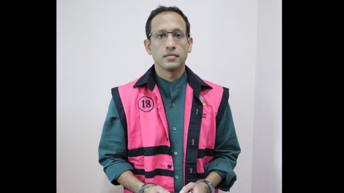 Nadiem Makarim saat mengenakan rompi pink dan kedua tangannya diborgol. 