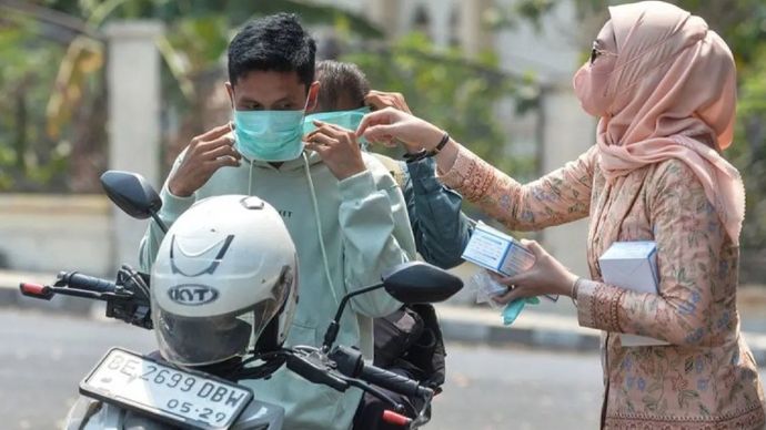 Pengendara sepeda motor memakai masker yang dibagikan anggota Dharma Wanita Persatuan (DWP) Kabupaten Lampung Selatan di Kalianda, Kabupaten Lampung Selatan, Lampung, Senin (7/9/2026).