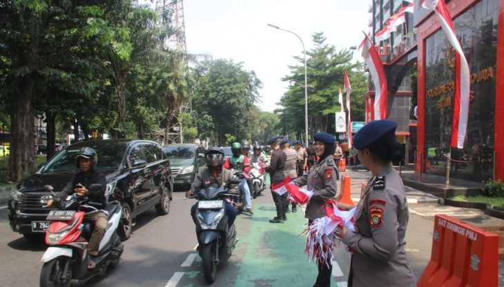 Personel Brimob Polda Metro Jaya membagikan bendera merah putih kepada sejumlah pengendara sepeda motor yang melintas di kawasan Jakarta Pusat, Senin 4 Agustus 2025. ANTARA/HO-Humas Polda Metro Jaya <b>(Antara)</b>