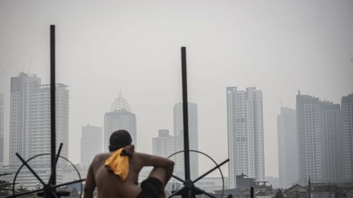 Ilustrasi - Seorang warga berjemur dengan latar belakang gedung bertingkat tersamar kabut polusi udara di Jakarta. ANTARA FOTO/Aprillio Akbar/rwa/aa. 