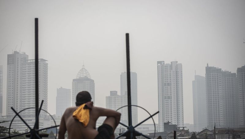 Ilustrasi - Seorang warga berjemur dengan latar belakang gedung bertingkat tersamar kabut polusi udara di Jakarta. ANTARA FOTO/Aprillio Akbar/rwa/aa.  <b>(ANTARA FOTO/Aprillio Akbar/rwa/aa.)</b>