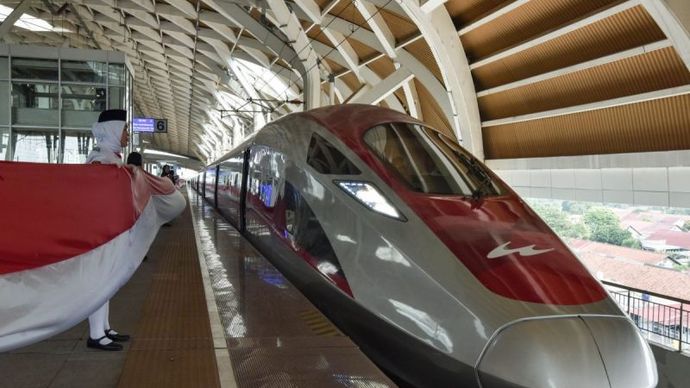 Petugas membentangkan bendera Merah Putih disamping Kereta Cepat Whoosh di Stasiun Kereta Cepat Halim, Jakarta Timur.  