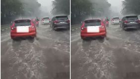 Hujan deras disertai angin kencang di beberapa wilayah di Jakarta menyebabkan banjir di Jalan Taman Mini, Jakarta Timur.