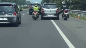 Dua anggota kepolisian menunjukkan aksi humanis dengan membantu sebuah mobil mogok di ruas Tol Cikopo-Palimanan (Cipali).