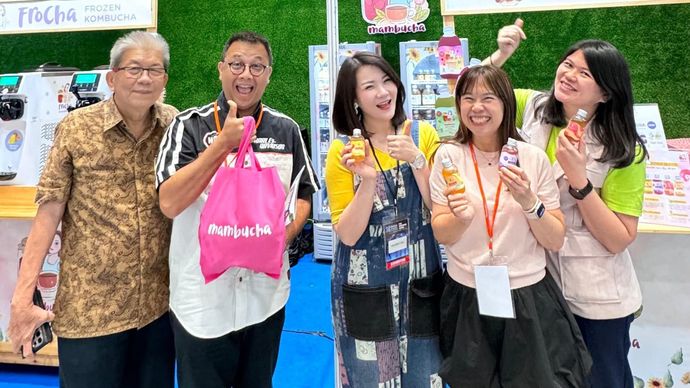 Anita Hartono (tengah) bersama tim Mambucha berpose di booth pameran. Melalui program pemberdayaan BRI Pengusaha Muda BRILiaN, Mambucha berhasil berkembang pesat dan mencatatkan prestasi sebagai pemenang Best of the Best kategori Healthcare/Wellness 