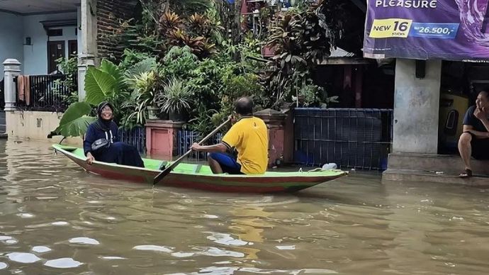 Dua orang warga di Desa Dayeuhkolot, Kecamatan Dayeuhkolot menaiki perahu setelah banjir setinggi 1,5 meter, Jumat 5 Desember 2025. 