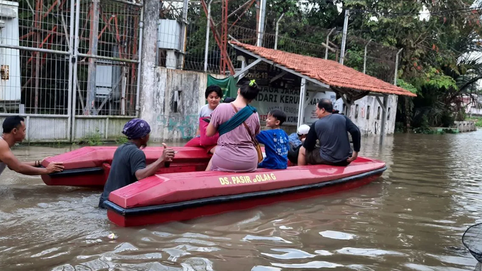 Sejumlah warga melintas genangan air menggunakan perahu karet saat hendak mengungsi ke tempat aman. 