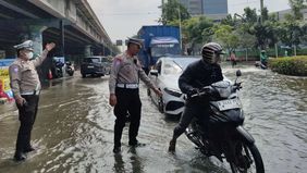 Petugas Kepolisian Lalu Lintas melakukan rekayasa di lampu merah Puri Kembangan, Jakarta Barat akibat banjir yang belum surut setelah hujan deras pada Senin malam kemarin, 7 Juli 2025.