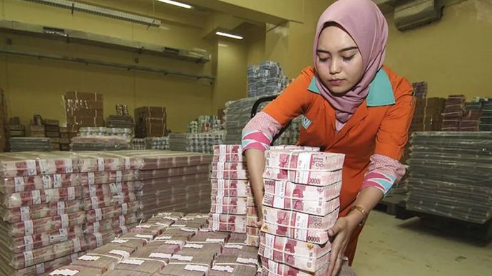 Ilustrasi - Petugas menata tumpukan uang kertas rupiah saat melakukan persiapan pengisian ATM.